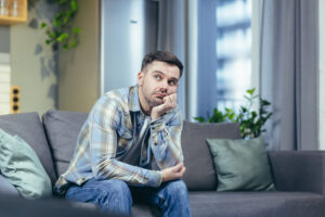 Image of reflective man sitting on his sofa, reflecting on his youth.